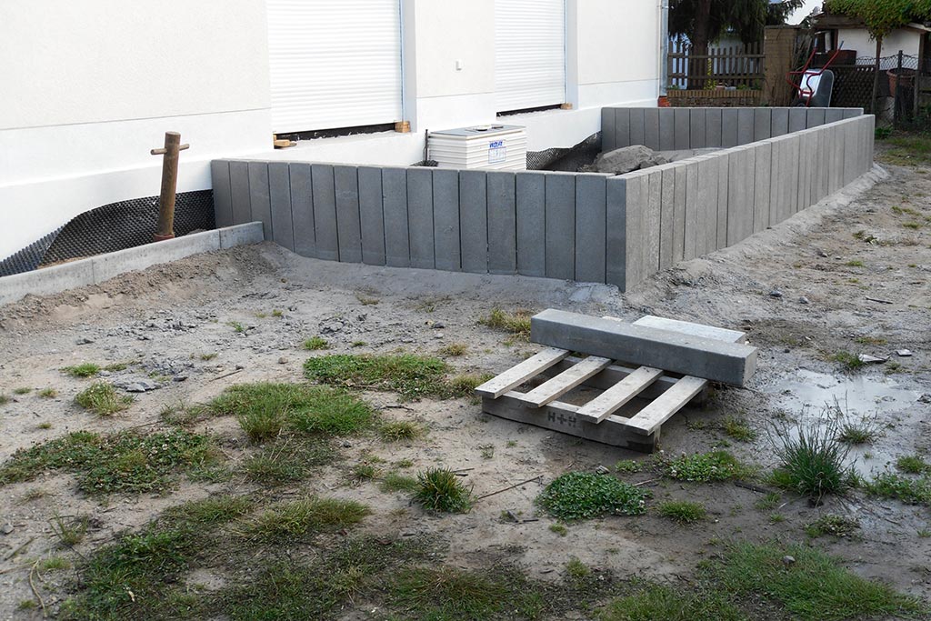 Gartenneuanlage nach Neubau - Setzen von Betonpalisaden als Einfassung einer erhöhten Terrasse