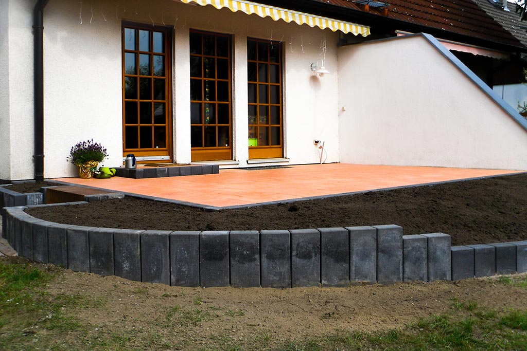 Gartenterrasse mit neu verlegten Betonplatten und angrenzendes Beet mit neuer Einfassung aus Betonpalisaden