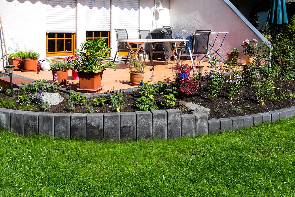Neugestaltete Gartenterrasse mit neuem Bodenbelag und neu bepflanztem anschließenden Beet